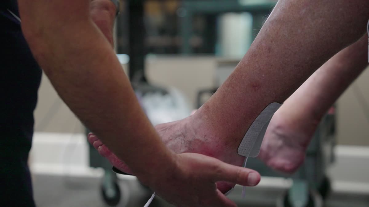 A REM specialist performing hands-on assessment of a client's lower limb.